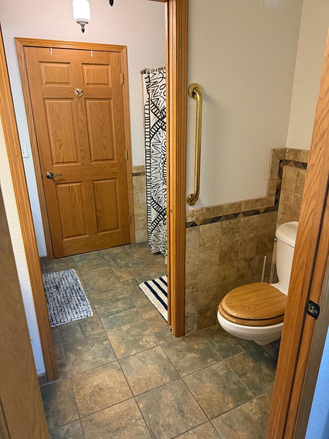33688 416th Ave, Farm Island Twp, MN 56431 - bathroom featuring tile walls, stone tile flooring, a wainscoted wall, and toilet