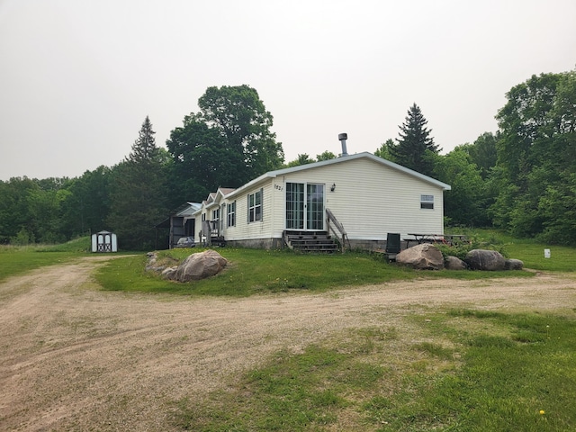 13505 580th Ave, Menahga, MN 56464 - view of side of home featuring entry steps, dirt driveway, a forest view, and a yard