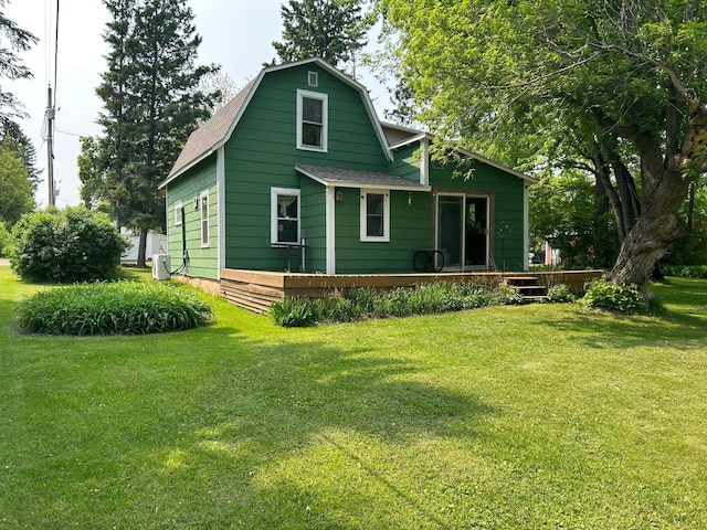 206 5th Ave, Palisade, MN 56469 - rear view of house with a gambrel roof, a wooden deck, a lawn, and roof with shingles