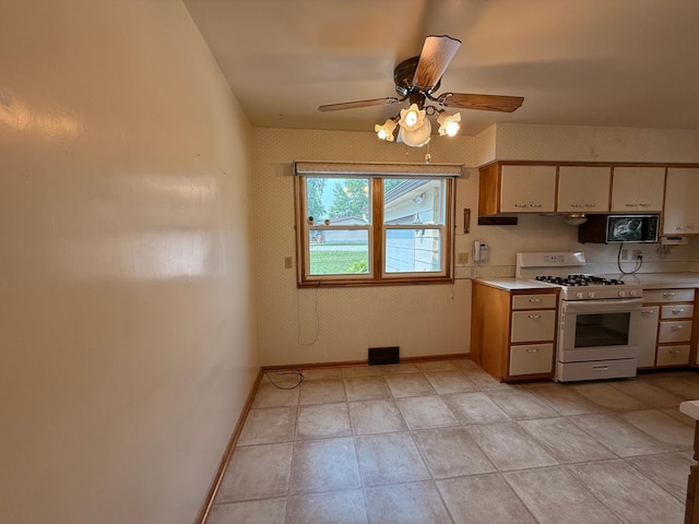 1620 4th St, Montevideo, MN 56265 - kitchen featuring white range with gas stovetop, light countertops, baseboards, ceiling fan, and black microwave