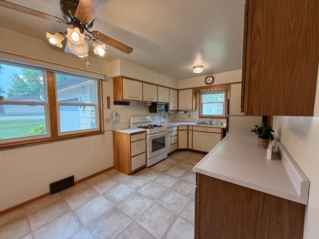1620 4th St, Montevideo, MN 56265 - kitchen with white appliances, wallpapered walls, light countertops, a sink, and a ceiling fan