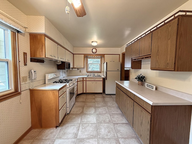 1620 4th St, Montevideo, MN 56265 - kitchen with white appliances, wallpapered walls, a sink, light countertops, and ceiling fan