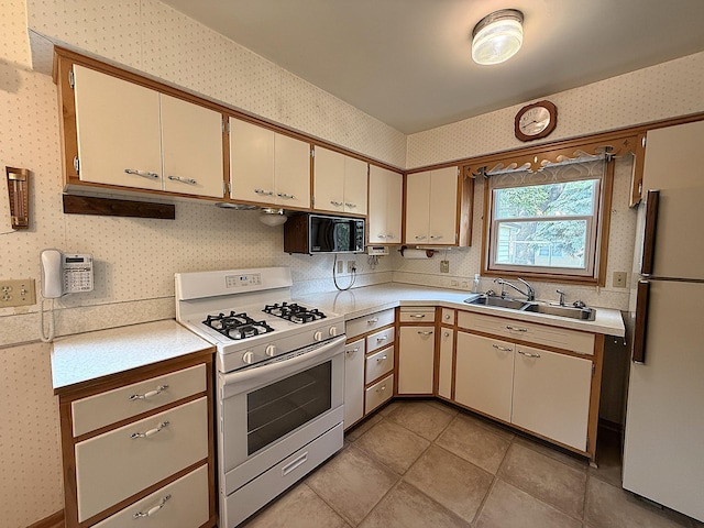 1620 4th St, Montevideo, MN 56265 - kitchen with white appliances, a sink, light countertops, wallpapered walls, and cream cabinetry