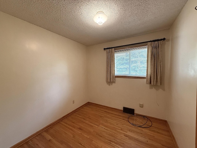 1620 4th St, Montevideo, MN 56265 - empty room featuring light wood-style flooring, baseboards, and a textured ceiling
