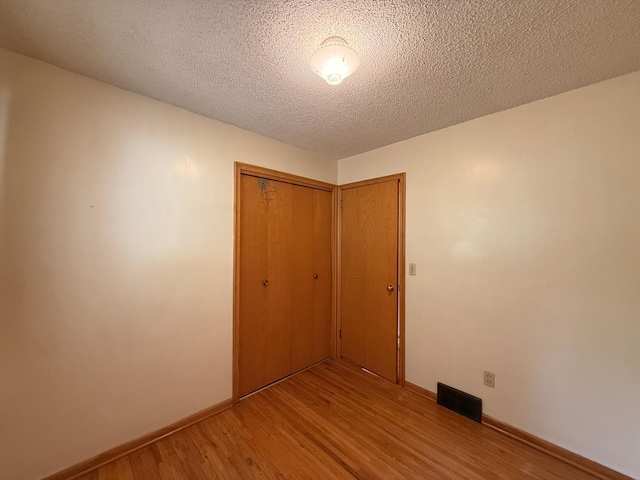 1620 4th St, Montevideo, MN 56265 - unfurnished bedroom featuring light wood-style flooring, a closet, baseboards, and a textured ceiling