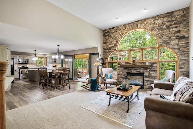 22774 Olivine St NW, Nowthen, MN 55330 - living room featuring light wood finished floors, a stone fireplace, a chandelier, and a high ceiling