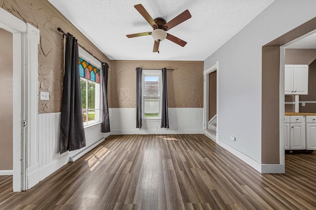 300 Ellington St, West Concord, MN 55985 - spare room with a baseboard heating unit, a ceiling fan, dark wood finished floors, a wainscoted wall, and a textured ceiling
