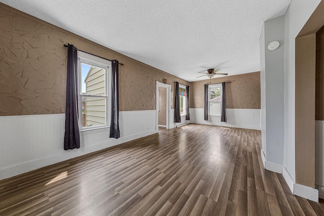 300 Ellington St, West Concord, MN 55985 - empty room featuring a textured ceiling, a wainscoted wall, a ceiling fan, wood finished floors, and wallpapered walls