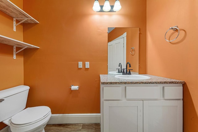 300 Ellington St, West Concord, MN 55985 - bathroom featuring toilet, vanity, baseboards, and wood finished floors