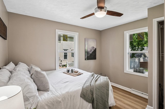 404 8th Ave S, Princeton, MN 55371 - bedroom featuring a baseboard heating unit, wood finished floors, baseboards, and ceiling fan