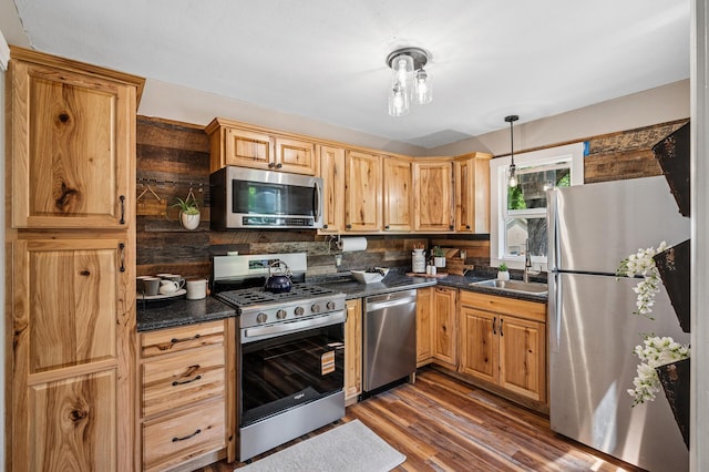 404 8th Ave S, Princeton, MN 55371 - kitchen featuring appliances with stainless steel finishes, a sink, dark countertops, dark wood-style floors, and decorative backsplash