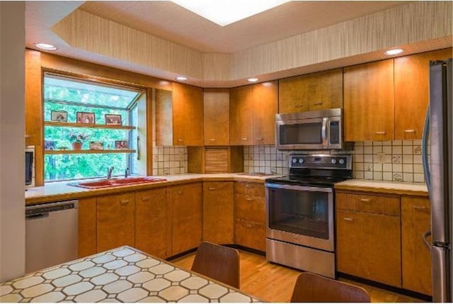 5157 Abercrombie Dr, Edina, MN 55439 - kitchen featuring appliances with stainless steel finishes, light countertops, brown cabinetry, and tasteful backsplash
