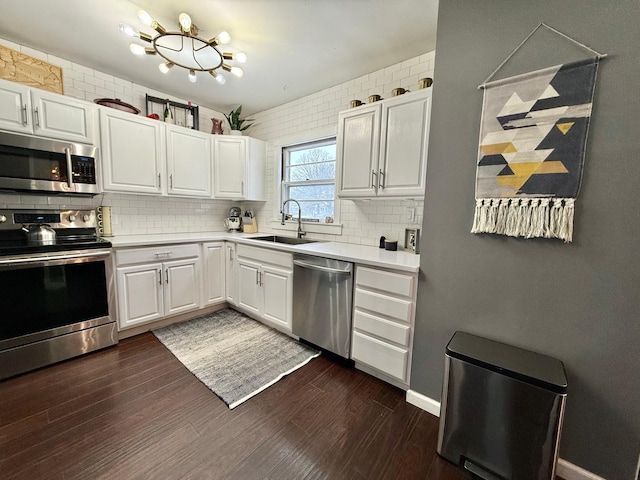310 Saint Paul Ave S, Thief River Falls, MN 56701 - kitchen featuring stainless steel appliances, a sink, backsplash, dark wood-style floors, and light countertops