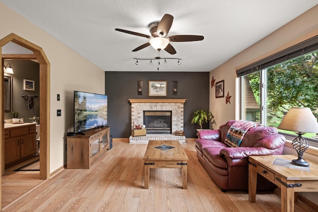 5641 146th Ave NW, Ramsey, MN 55303 - living area with light wood-style flooring, a ceiling fan, a fireplace, track lighting, and baseboards