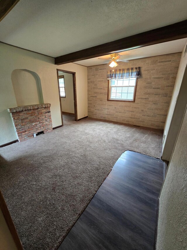 25 Morgan St, Tracy, MN 56175 - unfurnished living room featuring beam ceiling, plenty of natural light, ceiling fan, carpet, and brick wall
