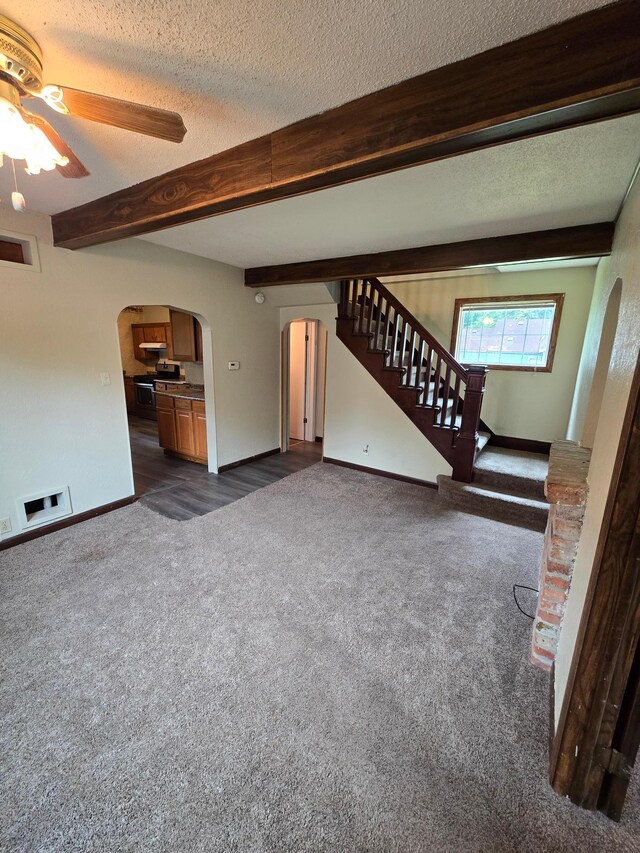 25 Morgan St, Tracy, MN 56175 - unfurnished living room featuring arched walkways, dark carpet, beamed ceiling, stairs, and a ceiling fan