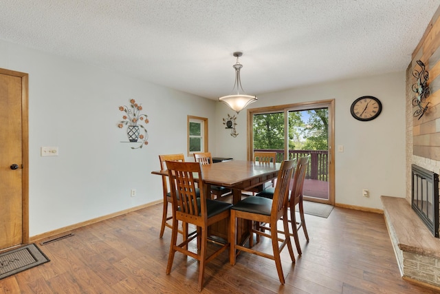 13100 Island View Dr NW, Elk River, MN 55330 - dining space with light wood-type flooring, a fireplace, a textured ceiling, and baseboards