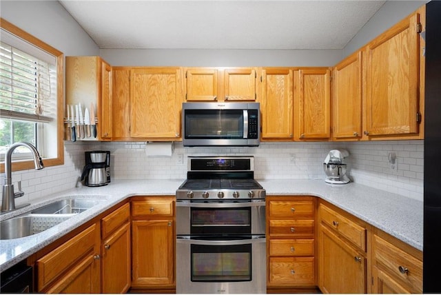 11509 Quay St, Coon Rapids, MN 55433 - kitchen with appliances with stainless steel finishes, a sink, tasteful backsplash, and light stone countertops