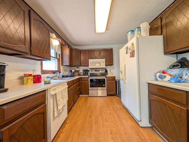 1422 6th St SE, Wadena, MN 56482 - kitchen featuring white appliances, light wood finished floors, a sink, and light countertops