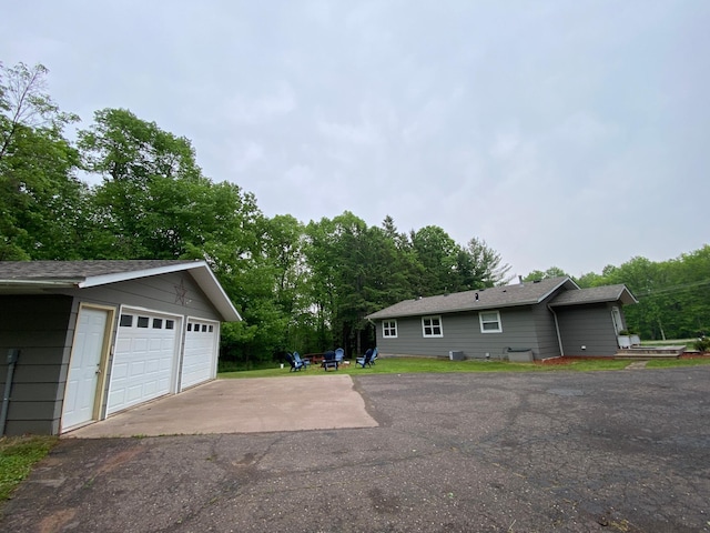 3771 County Line Rd, Moose Lake Twp, MN 55783 - view of side of property with an outdoor structure, a detached garage, roof with shingles, and view of wooded area