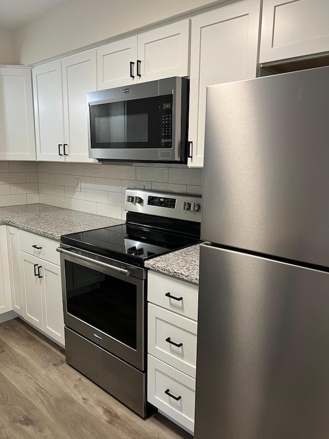 751 Sand Hill Pt, North Hudson, WI 54016 - kitchen featuring stainless steel appliances, light wood-style flooring, tasteful backsplash, and white cabinets