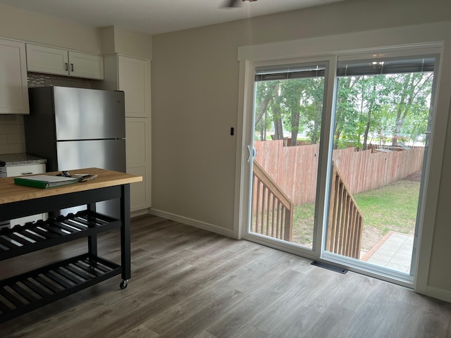 751 Sand Hill Pt, North Hudson, WI 54016 - kitchen with freestanding refrigerator, wood finished floors, white cabinetry, backsplash, and baseboards