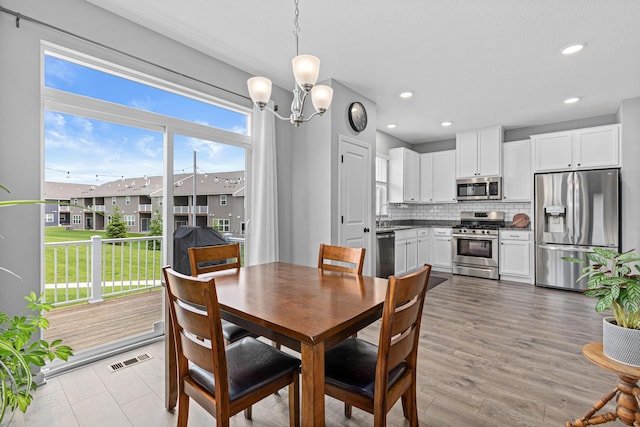 8756 Granite Ln, Woodbury, MN 55129 - dining area featuring a chandelier, recessed lighting, wood finished floors, and a residential view