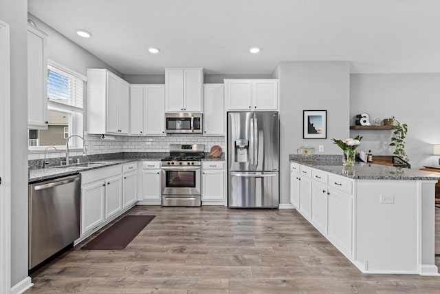 8756 Granite Ln, Woodbury, MN 55129 - kitchen with appliances with stainless steel finishes, a sink, a peninsula, white cabinets, and recessed lighting