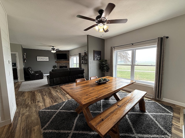 2771 271st Ave, Madison, MN 56256 - dining room with a ceiling fan, dark wood-style floors, baseboards, a fireplace, and a textured ceiling