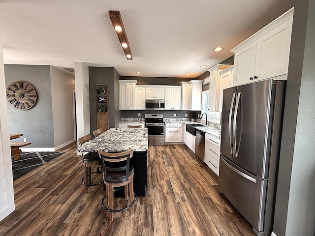2771 271st Ave, Madison, MN 56256 - kitchen with appliances with stainless steel finishes, light stone counters, dark wood-type flooring, white cabinetry, and a center island