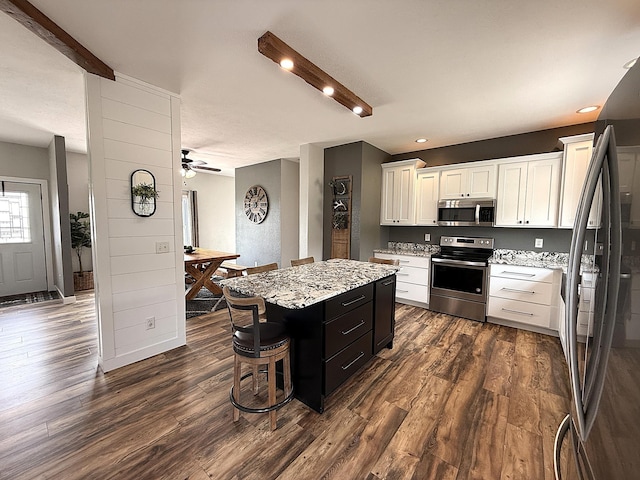 2771 271st Ave, Madison, MN 56256 - kitchen featuring appliances with stainless steel finishes, dark wood-style floors, white cabinetry, a center island, and light stone countertops