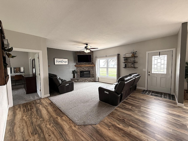 2771 271st Ave, Madison, MN 56256 - living room with a ceiling fan, dark wood finished floors, a fireplace, a textured ceiling, and baseboards