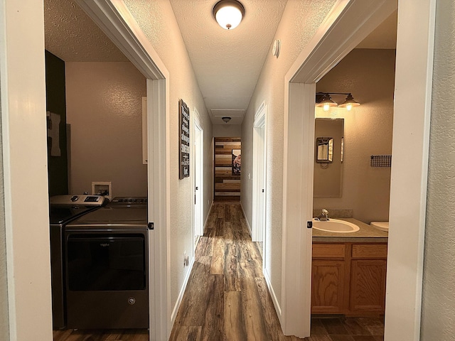2771 271st Ave, Madison, MN 56256 - hallway with washer and clothes dryer, dark wood finished floors, a textured wall, a sink, and a textured ceiling