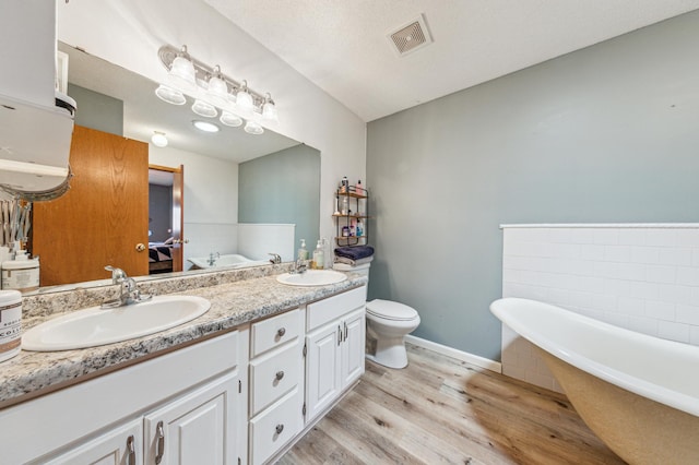 10344 Fox Run Rd, Woodbury, MN 55129 - bathroom with wood finished floors, a freestanding tub, double vanity, and toilet