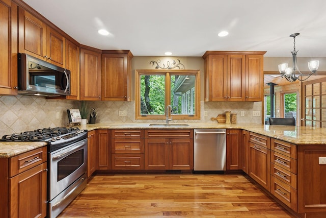 5921 Creek Pt, Minnetonka, MN 55345 - kitchen with appliances with stainless steel finishes, a sink, a peninsula, light wood-style floors, and a chandelier