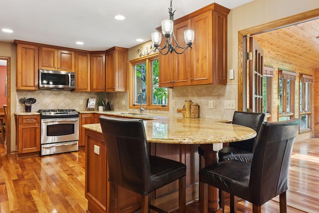 5921 Creek Pt, Minnetonka, MN 55345 - kitchen featuring stainless steel appliances, a peninsula, brown cabinets, light wood-style floors, and recessed lighting