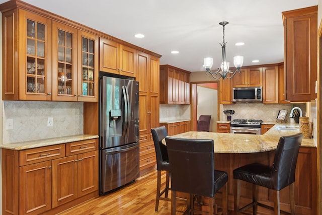 5921 Creek Pt, Minnetonka, MN 55345 - kitchen with stainless steel appliances, a sink, a peninsula, light stone counters, and glass insert cabinets