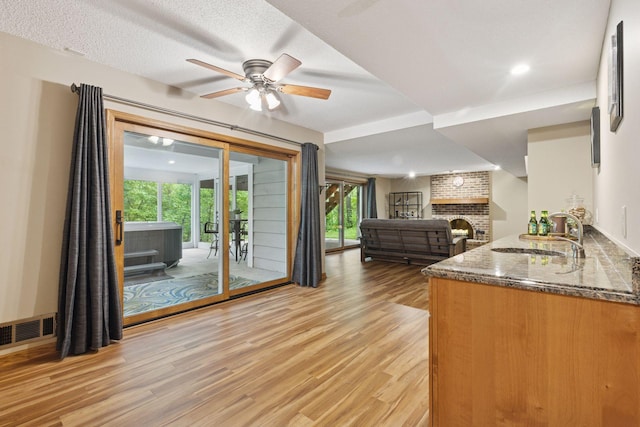 5921 Creek Pt, Minnetonka, MN 55345 - kitchen featuring light wood-style floors, a sink, dark stone counters, a ceiling fan, and a brick fireplace