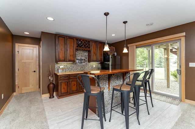 2292 Teakwood Ln SW, Rochester, MN 55902 - kitchen featuring freestanding refrigerator, tasteful backsplash, a kitchen breakfast bar, baseboards, and recessed lighting