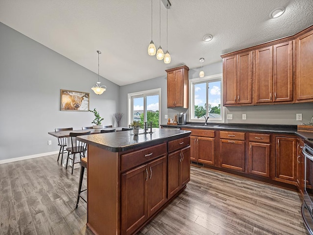 1308 Timber Ln, Buffalo, MN 55313 - kitchen featuring dark countertops, wood finished floors, vaulted ceiling, a kitchen breakfast bar, and a kitchen island