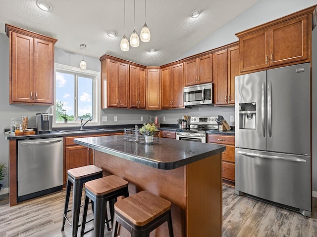 1308 Timber Ln, Buffalo, MN 55313 - kitchen featuring appliances with stainless steel finishes, dark countertops, light wood-type flooring, brown cabinets, and a textured ceiling