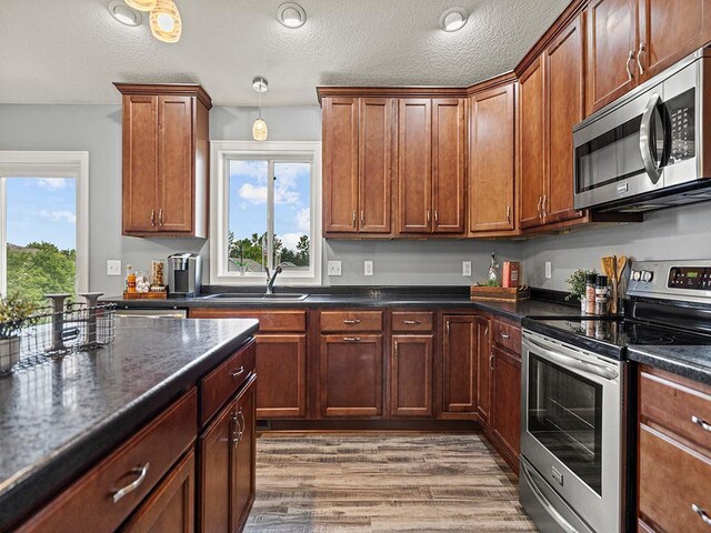 1308 Timber Ln, Buffalo, MN 55313 - kitchen with stainless steel appliances, healthy amount of natural light, light wood-style floors, a textured ceiling, and pendant lighting