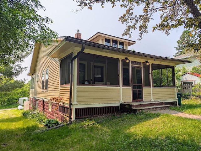 222 Ione Ave NE, Hill City, MN 55748 - back of house with a sunroom, a chimney, and a lawn