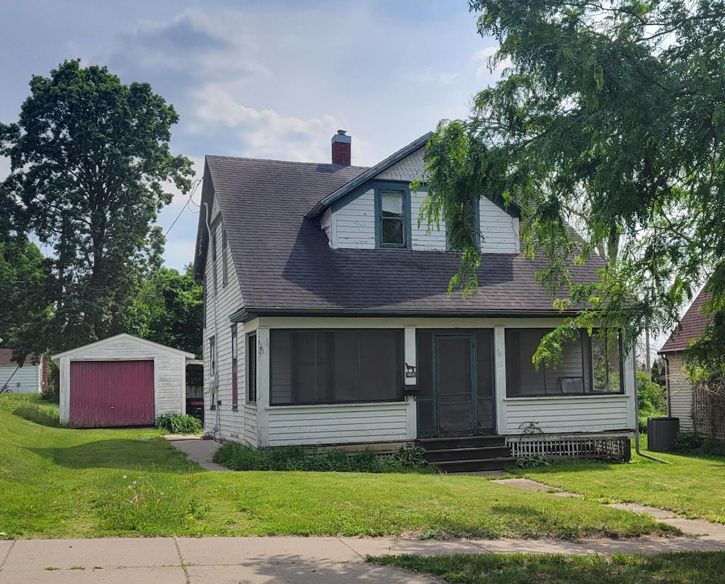 1503 6th St, Red Wing, MN 55066 - view of front of home with a sunroom, an outbuilding, a front lawn, and a shingled roof