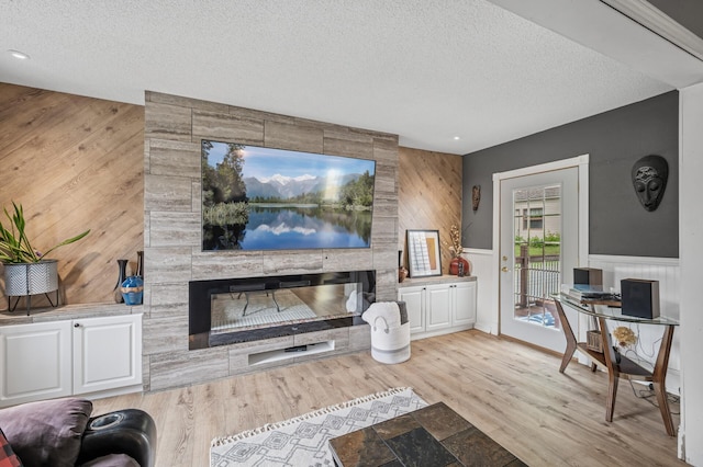 631 Bench St, Taylors Falls, MN 55084 - living room featuring a textured ceiling, wood finished floors, a tile fireplace, wooden walls, and wainscoting