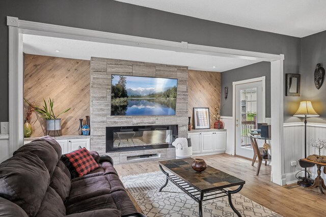 631 Bench St, Taylors Falls, MN 55084 - living room with light wood-style floors, wood walls, a tiled fireplace, and wainscoting