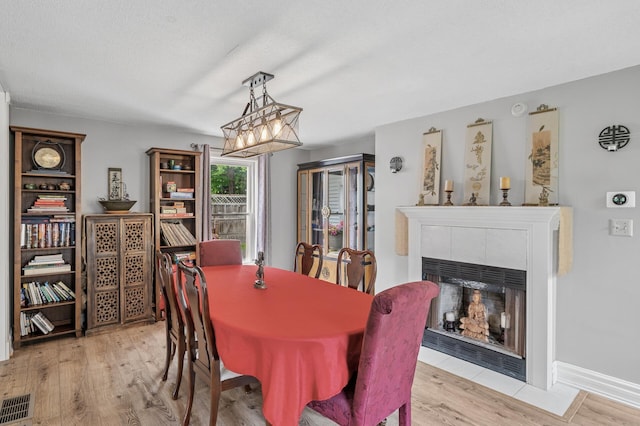631 Bench St, Taylors Falls, MN 55084 - dining area featuring a chandelier, light wood-style floors, and a tile fireplace