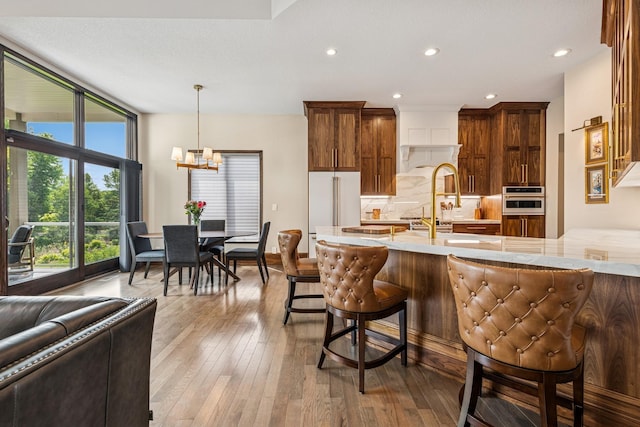 11883 Flanders Cir NE, Blaine, MN 55449 - kitchen with high end fridge, a chandelier, light countertops, backsplash, and a kitchen breakfast bar