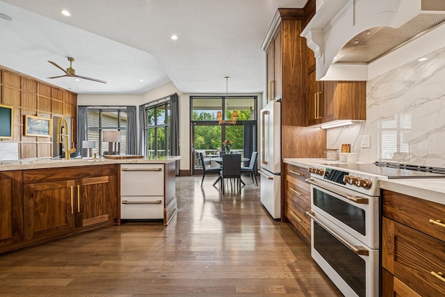 11883 Flanders Cir NE, Blaine, MN 55449 - kitchen with white appliances, custom exhaust hood, brown cabinets, light countertops, and dark wood finished floors