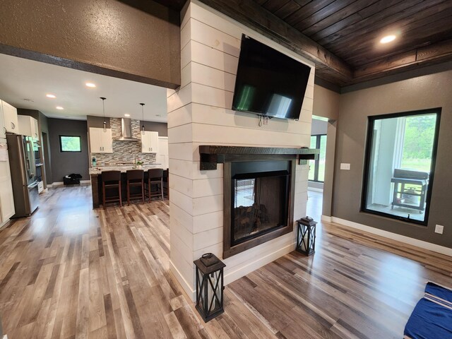 26575 US-71, Arago Twp, MN 56470 - living area featuring light wood finished floors, baseboards, a multi sided fireplace, recessed lighting, and wooden ceiling